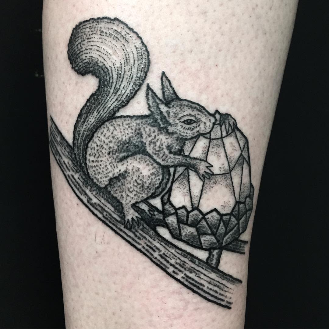 Tattoo of a squirrel hugging a large gemstone while perched on a tree branch